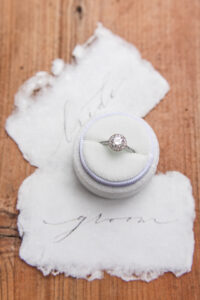 Wedding ring in white ring box laying on top of bride and groom cards. Texas wedding photography.